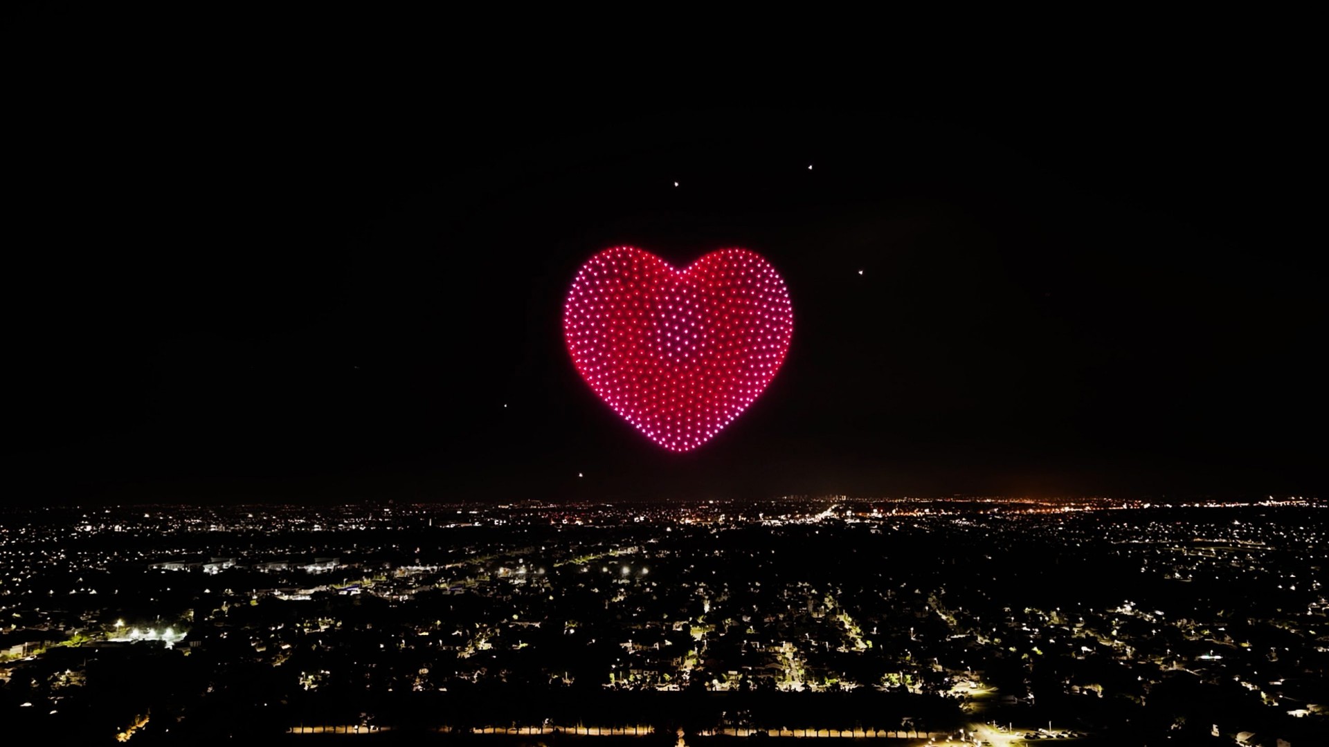 Heart formation drone show above suburban skyline
