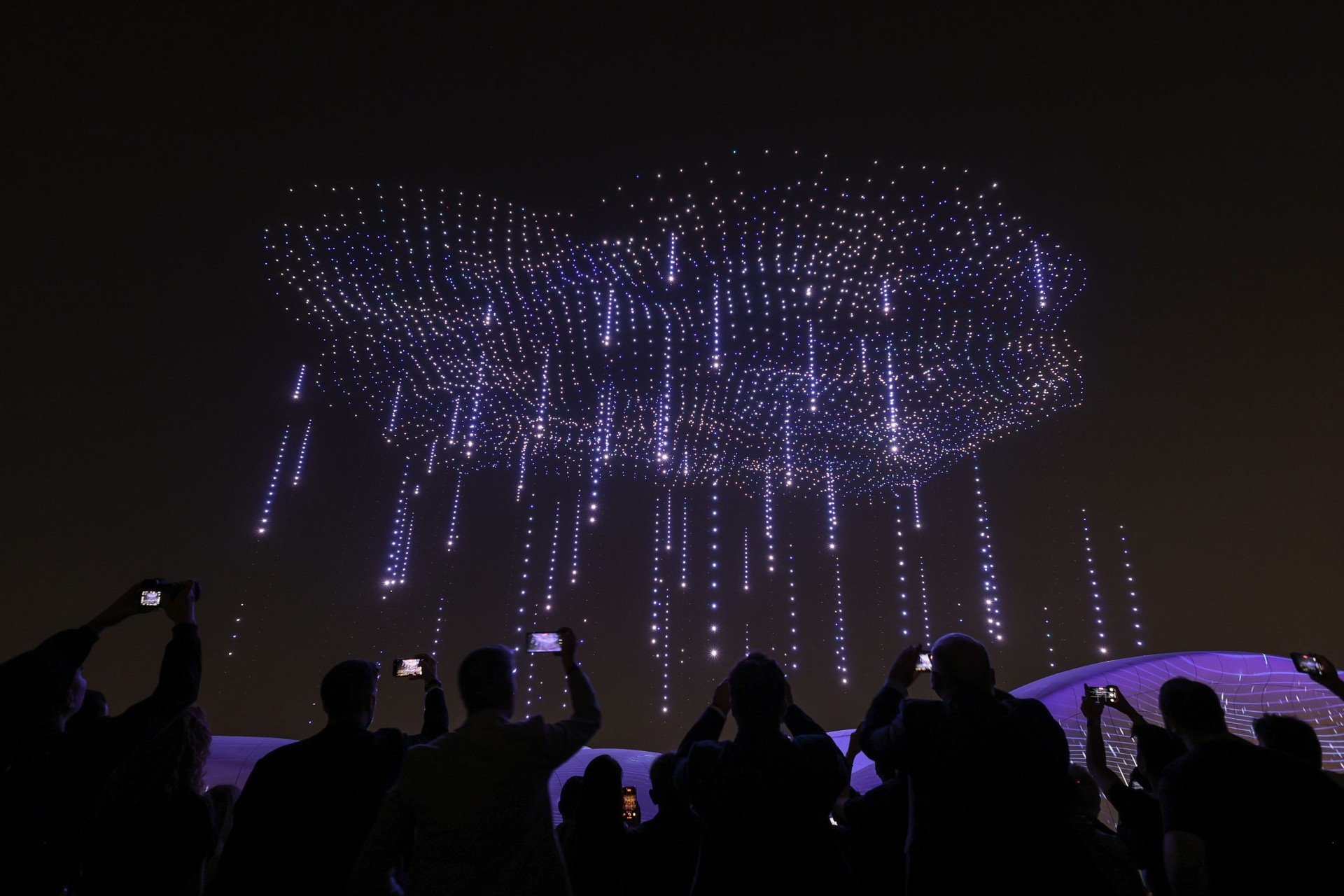 Cloud of light particles raining down over an audience